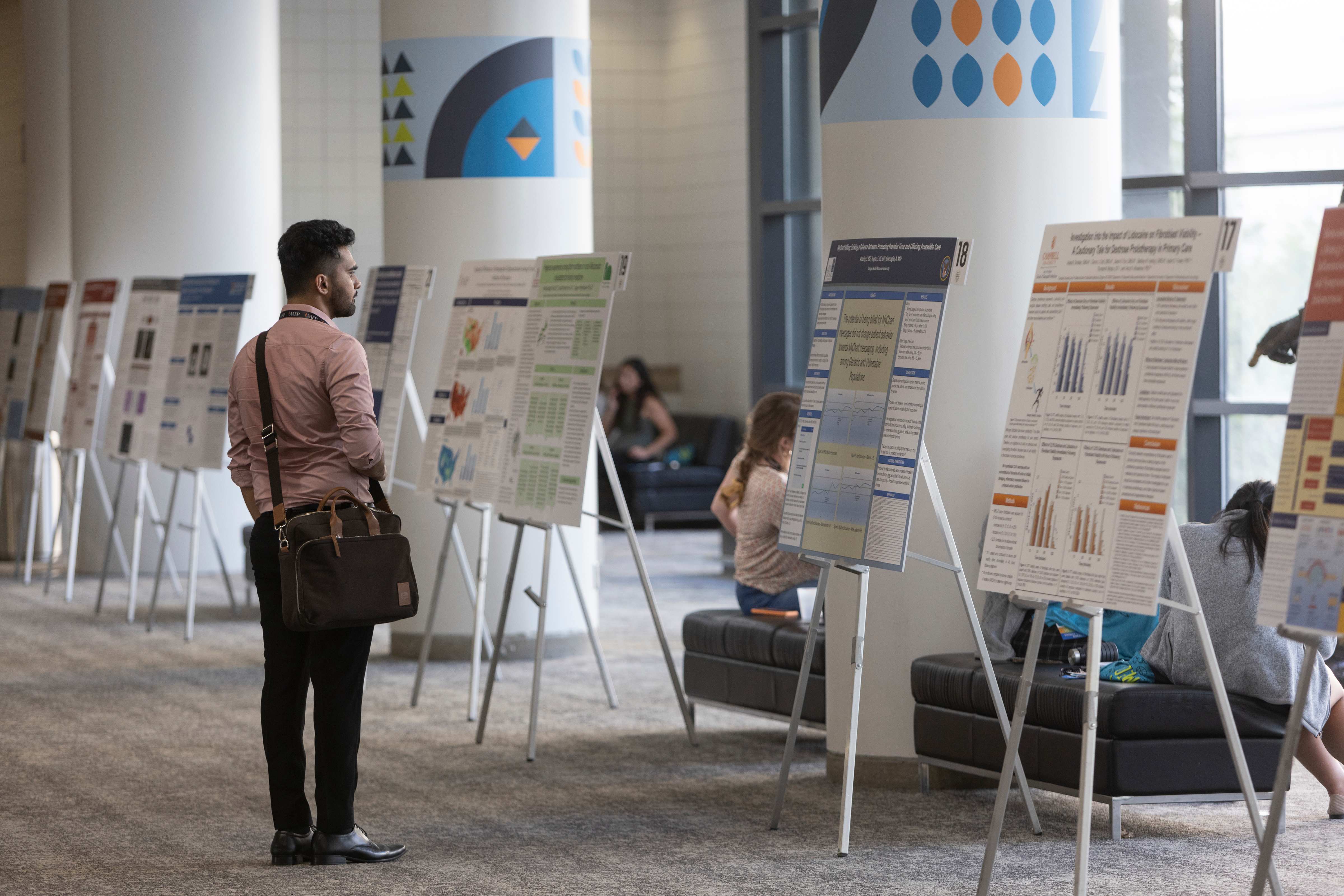 Conference attendee looking at display of research posters.