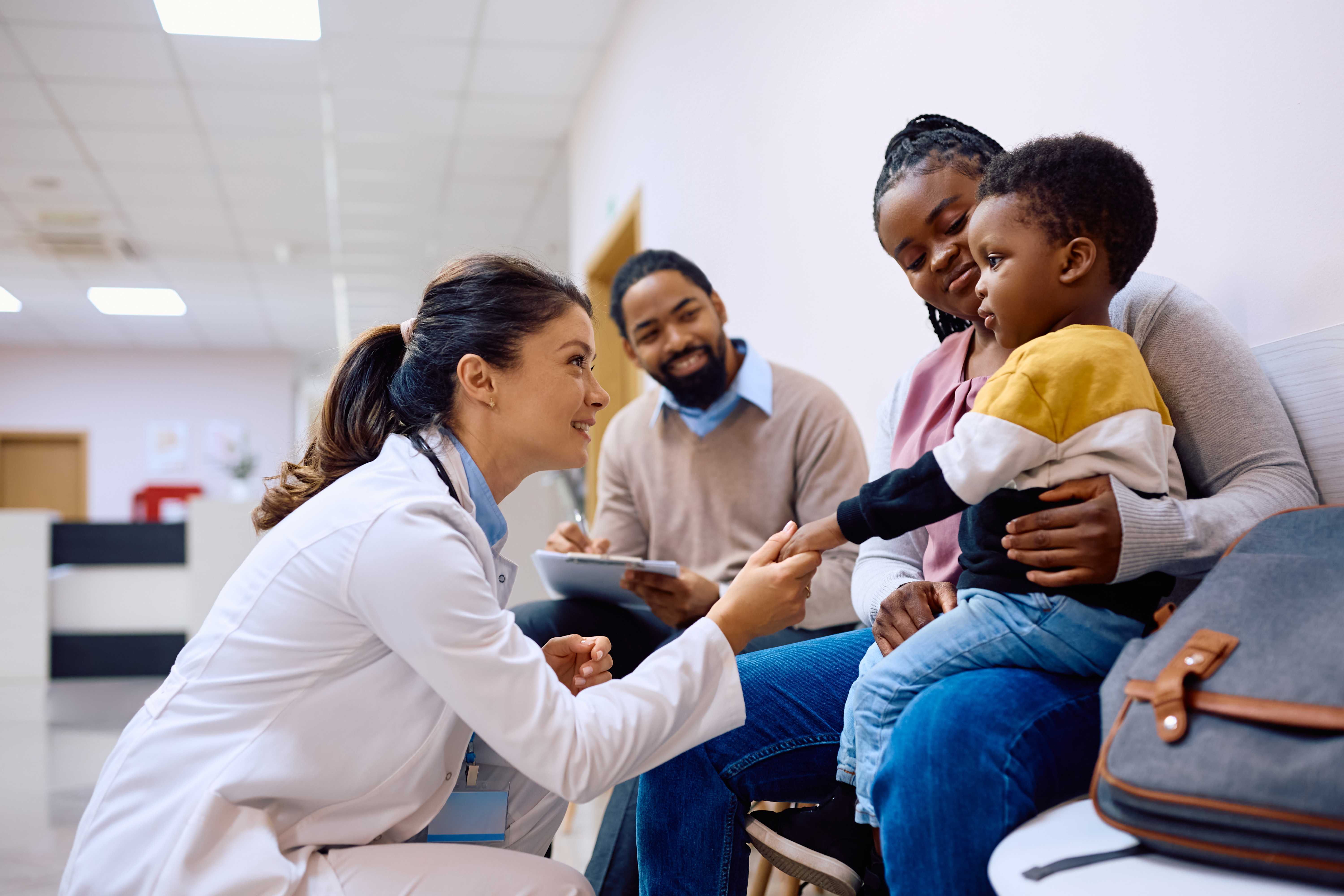 Female doctor with young patient and family.