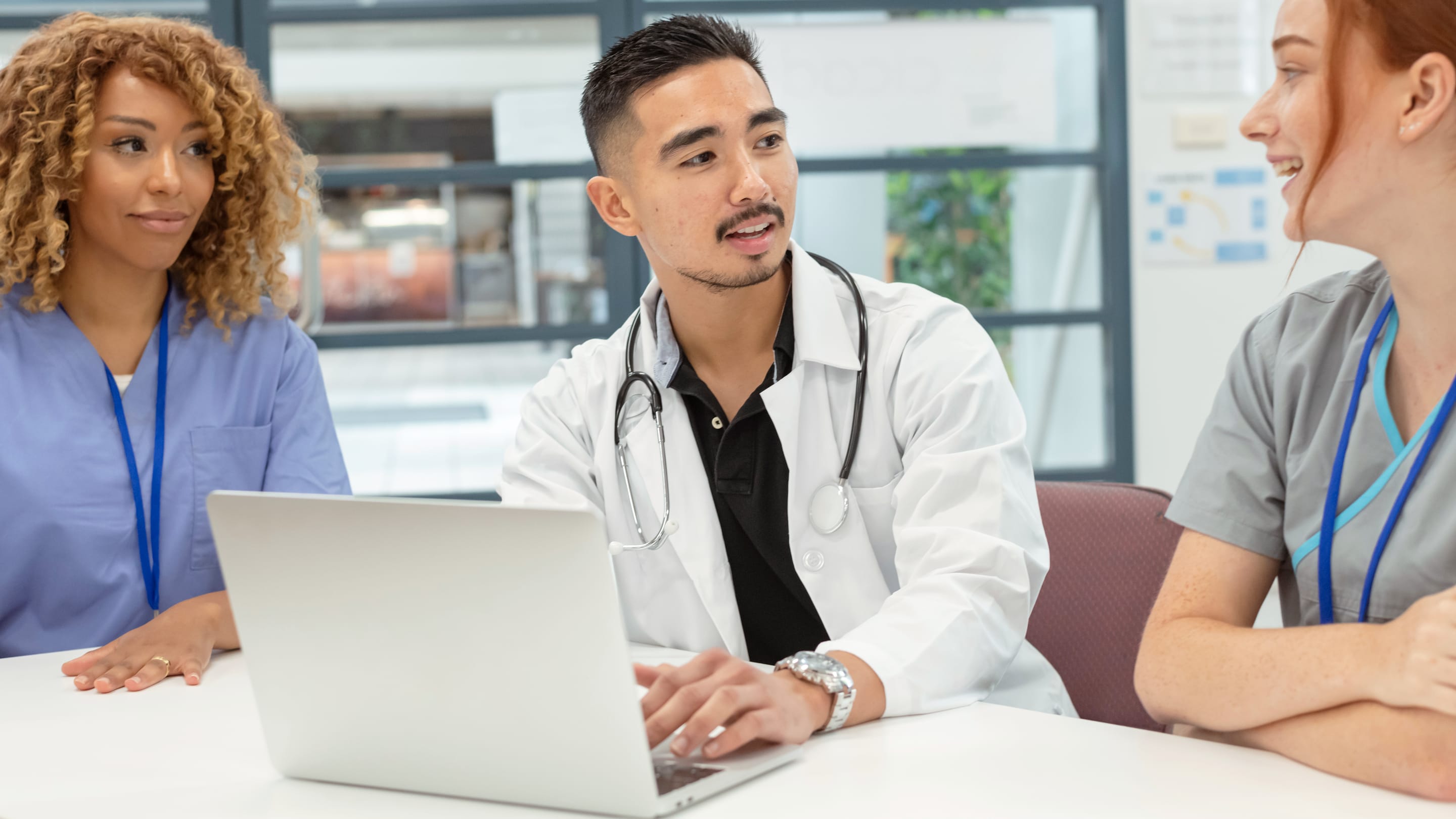 Image of early career family physician talking to peers in board meeting.