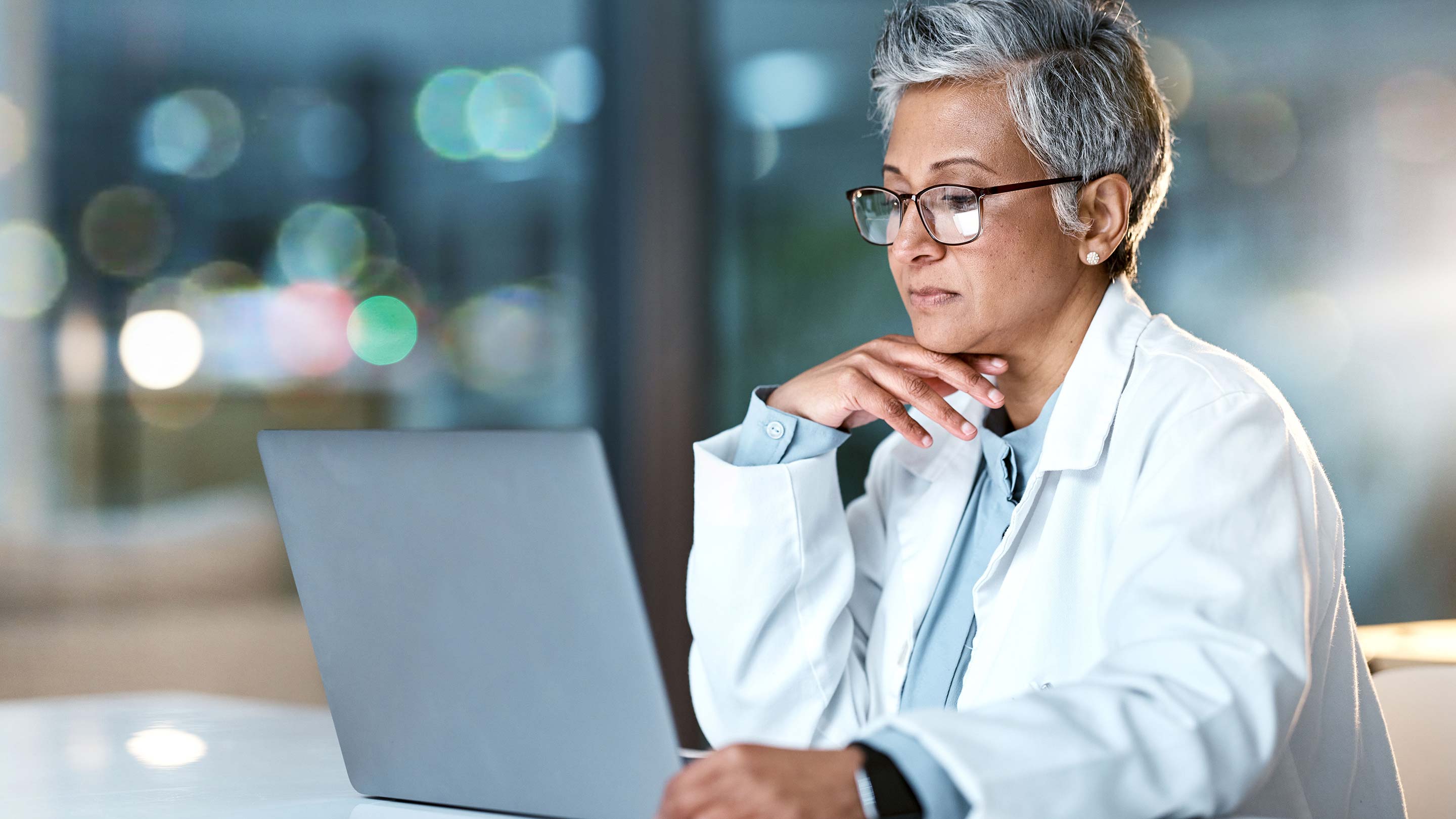 Woman sitting at computer, working on coding.