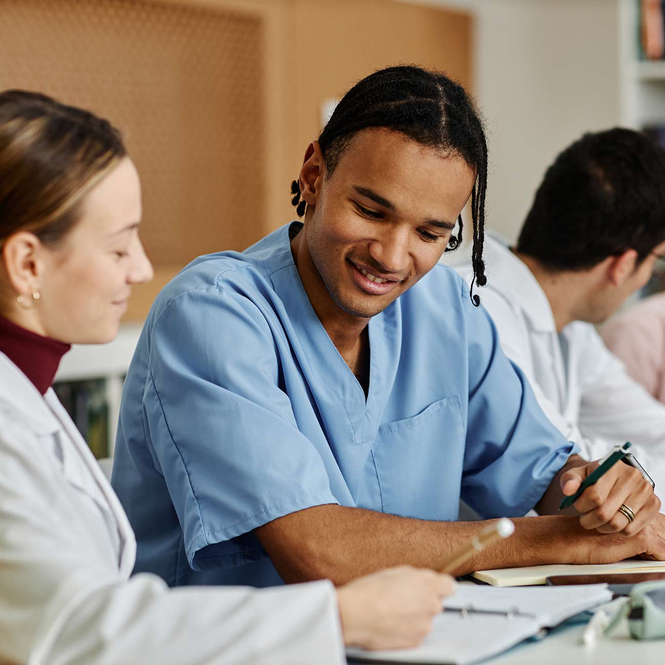 Diverse group of young medical professionals at table during meeting or seminar