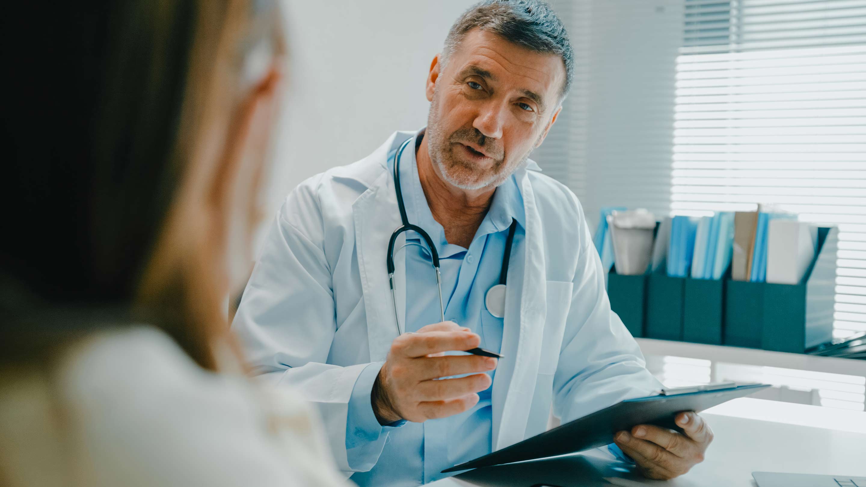 Male doctor at desk discussing payment with his patient.