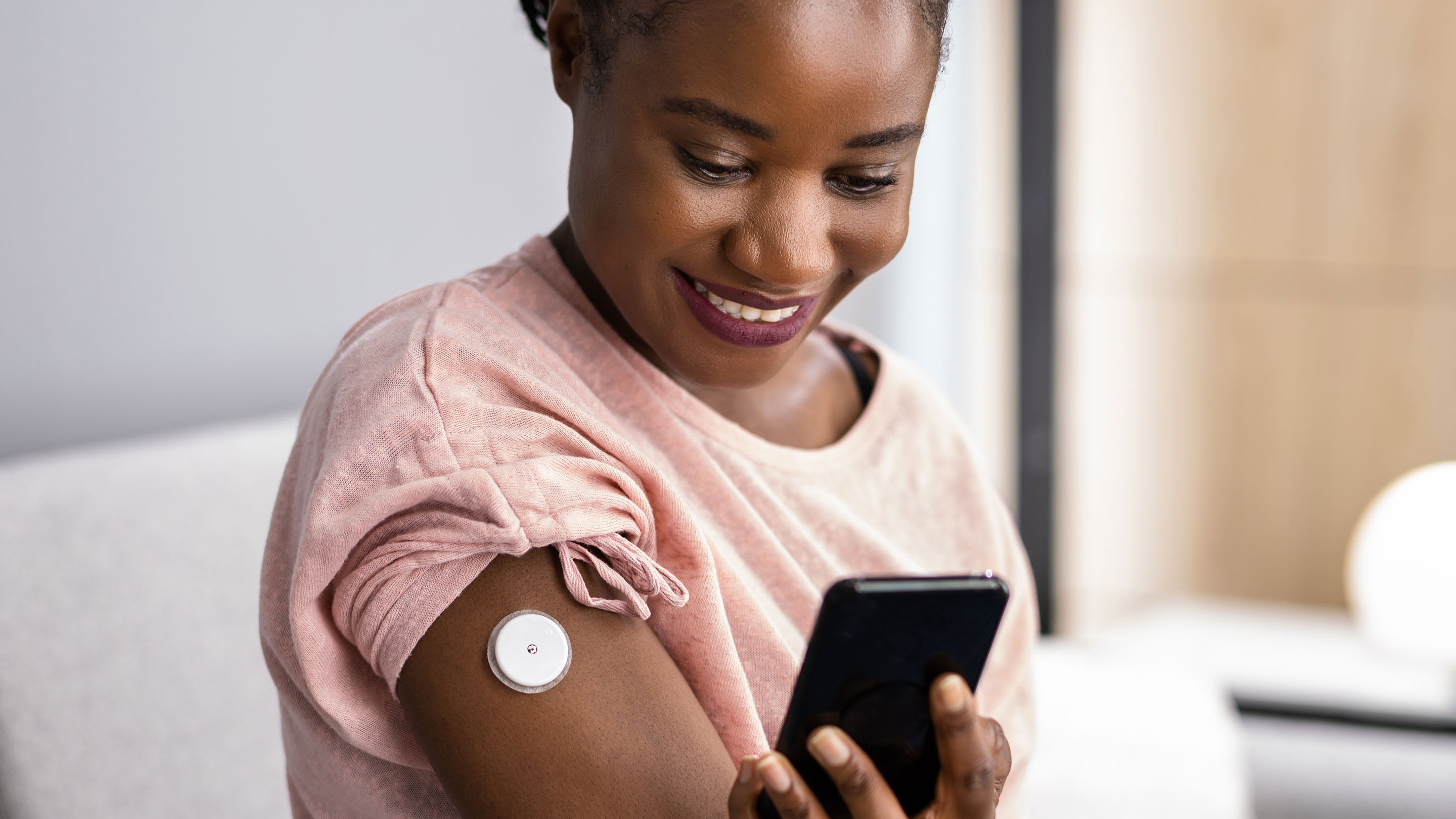 Woman testing glucose level with continuous glucose monitor on mobile phone