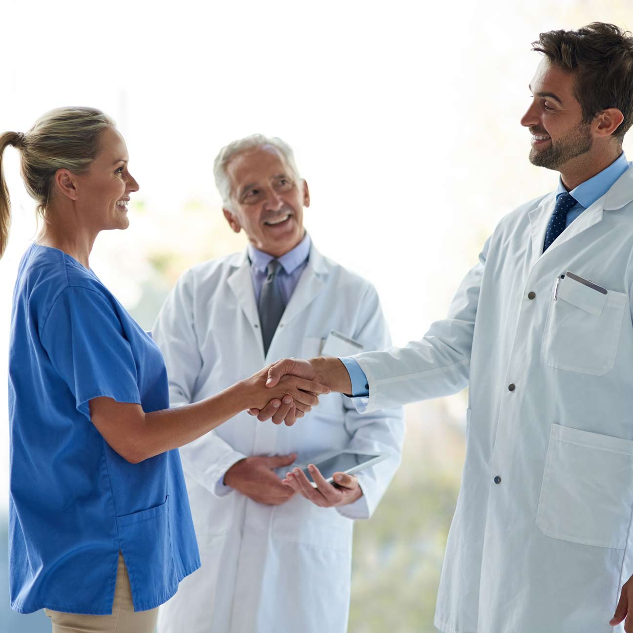 Nurse and resident physician shaking hands for onboarding, training, and introduction.