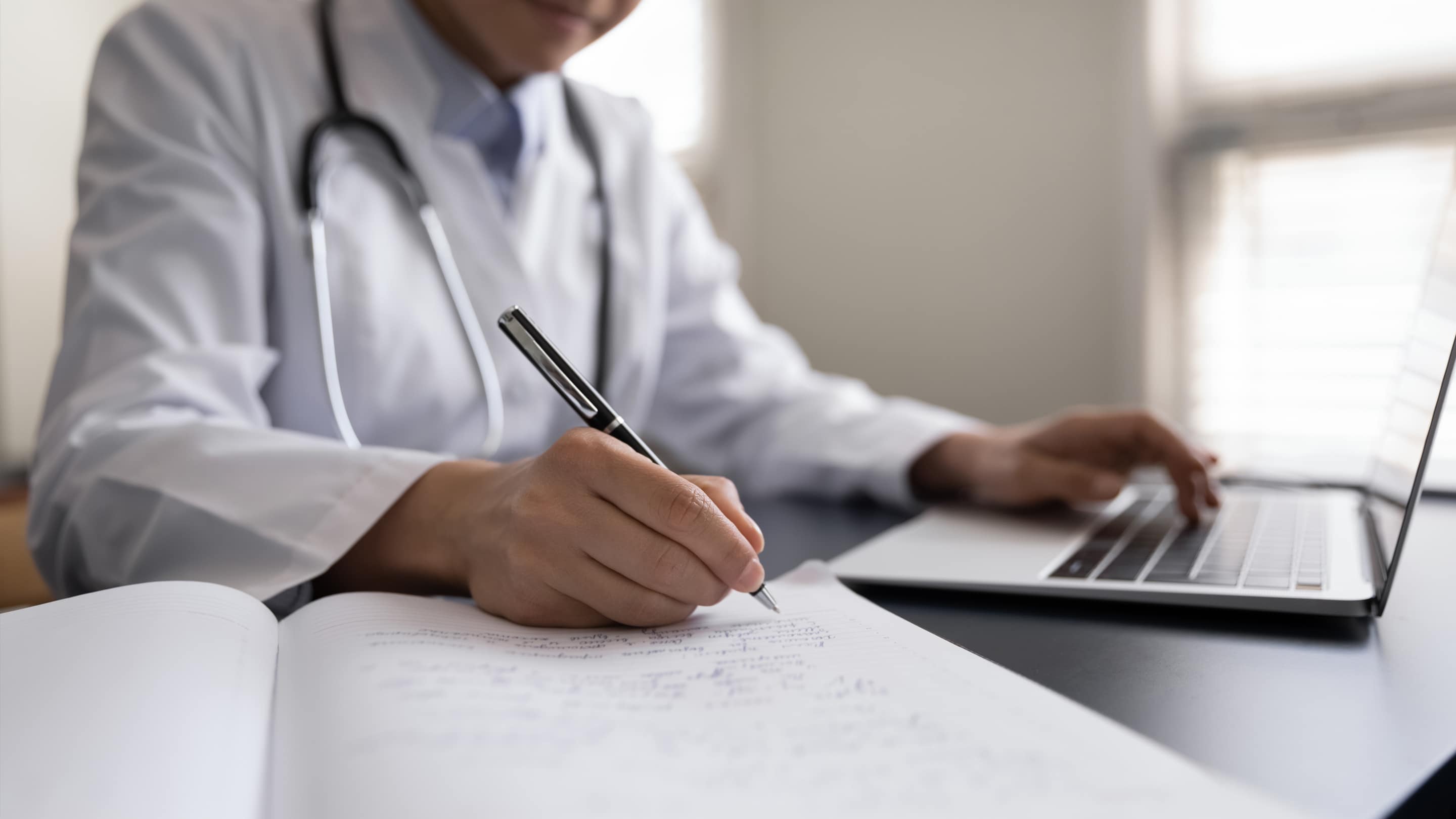 Physician at a computer taking notes on CME course.