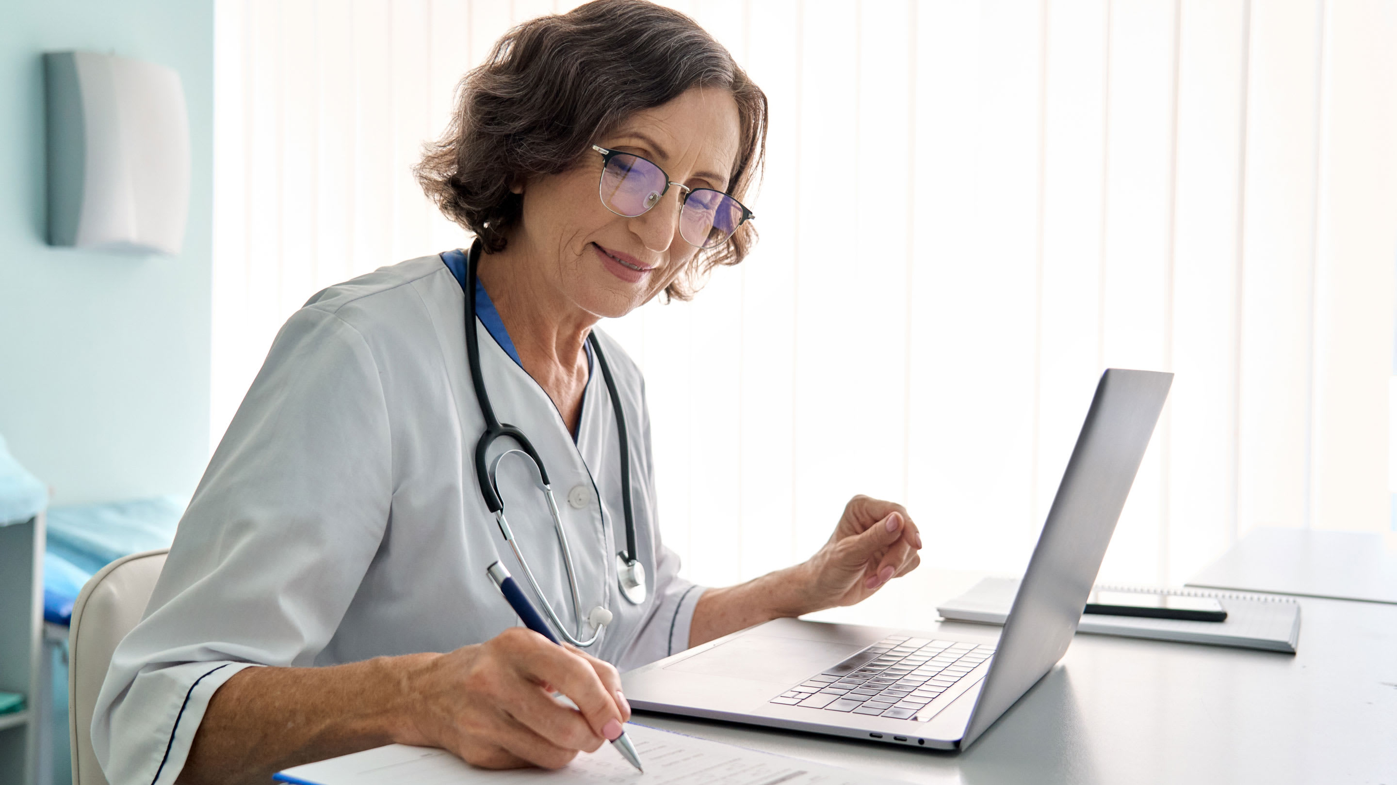 image of a physician in modern clinic using an assessment tool on laptop.