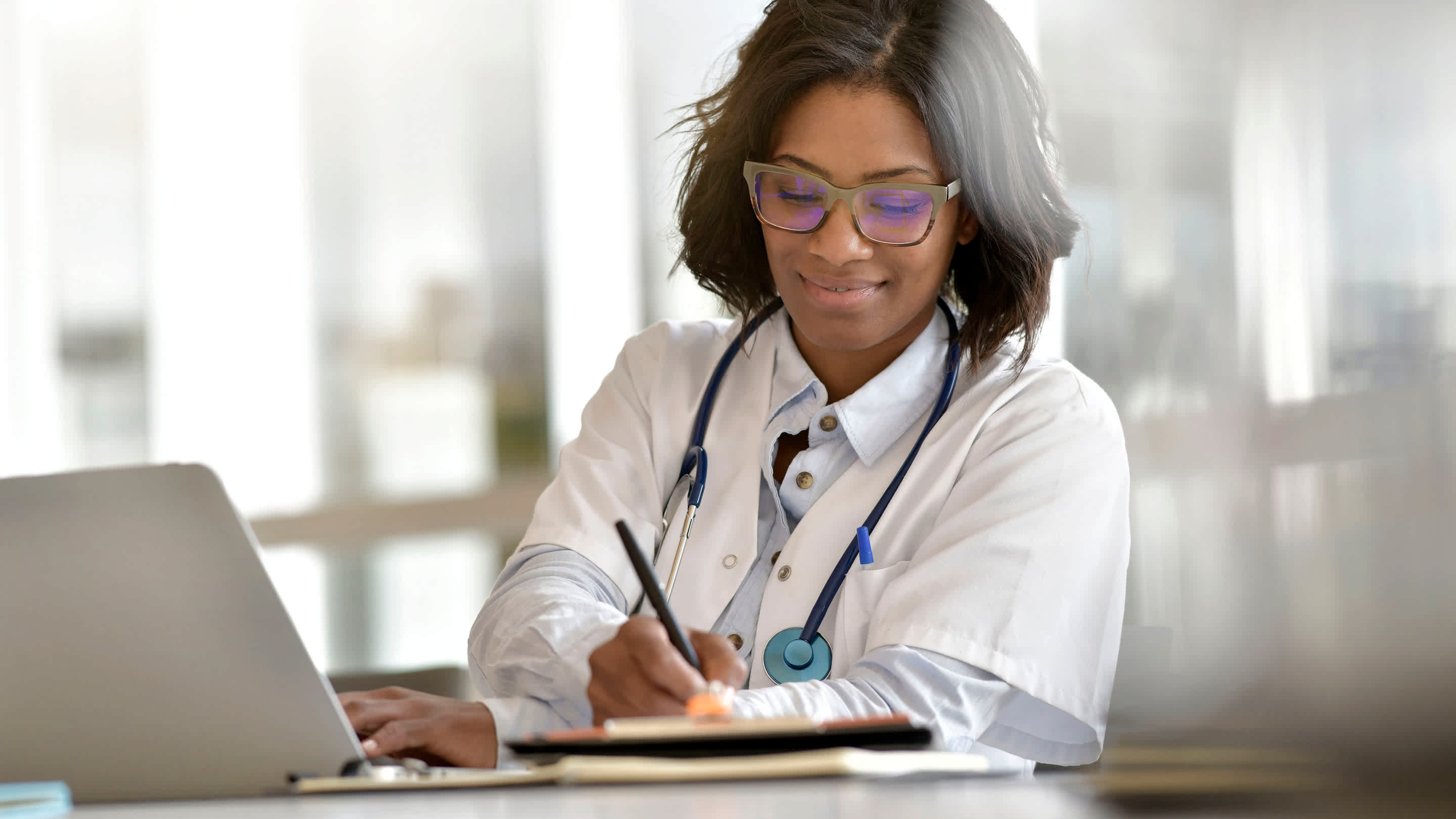 Physician working in an office at a laptop computer.