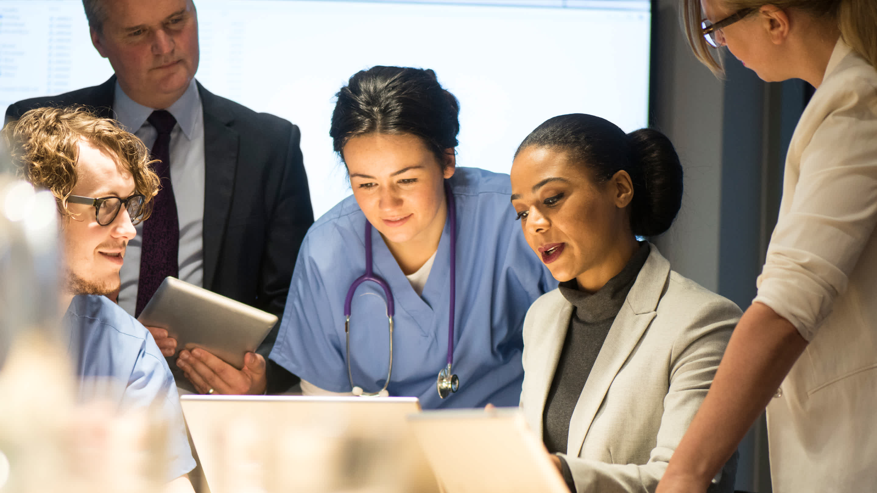 Doctors sitting around a table and laptop consulting over a patient.