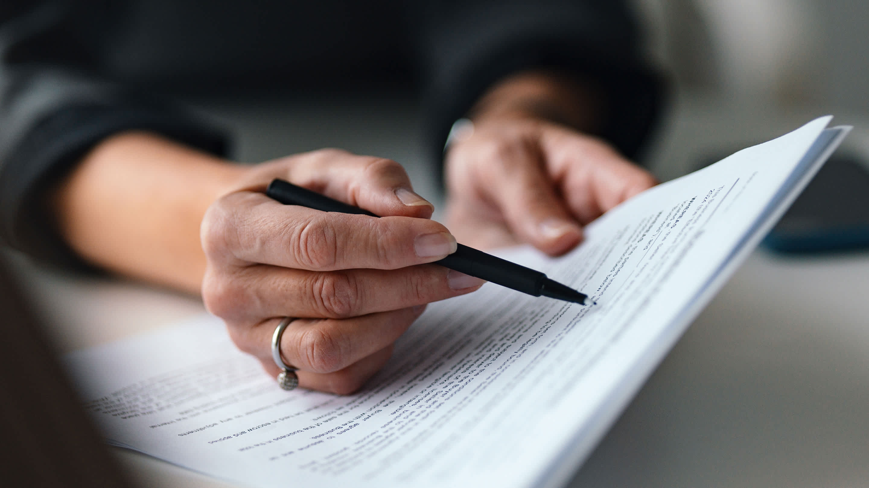 Hand holding legal agreement, studying and reading an employment contract.