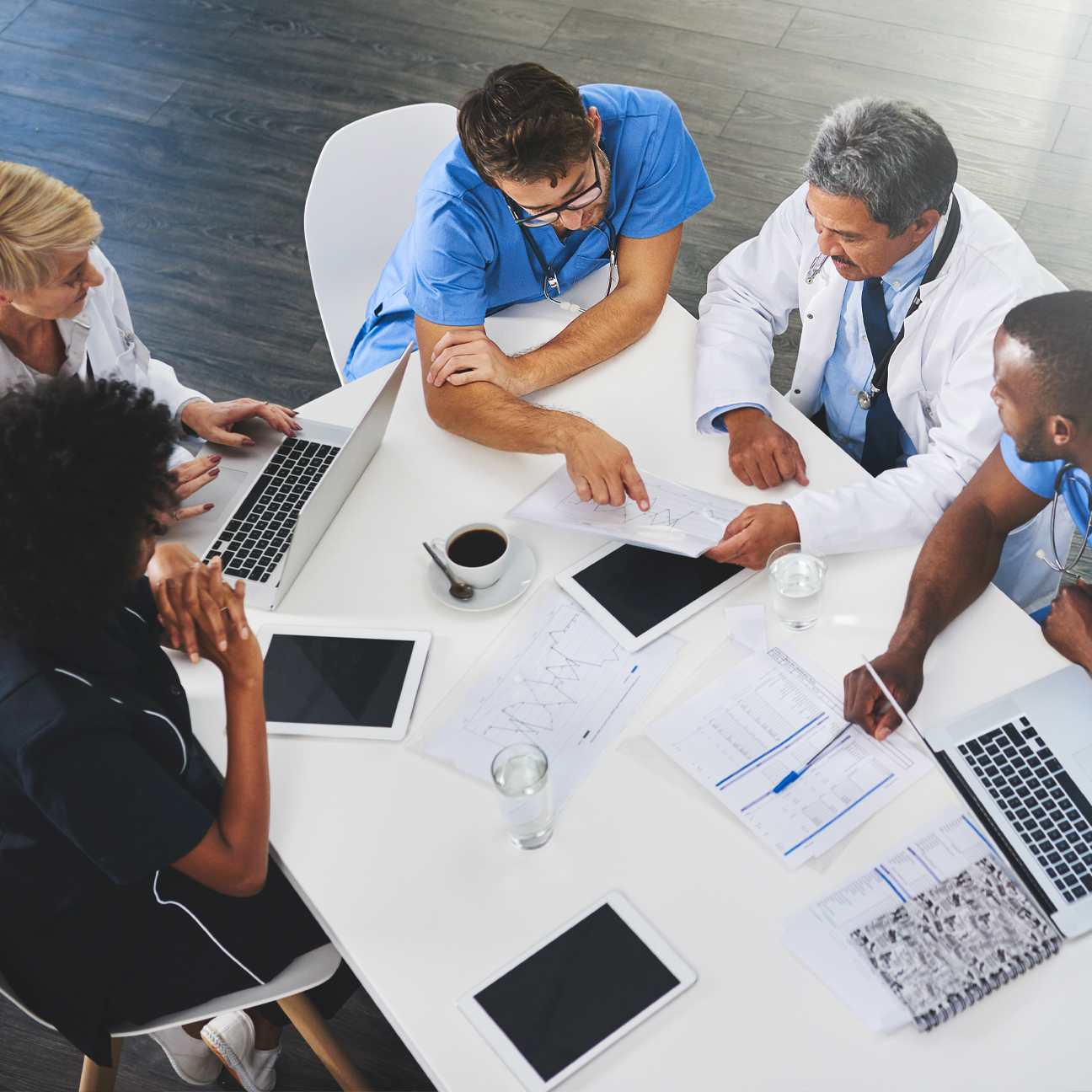 Medical team sitting and meeting with laptops around table.