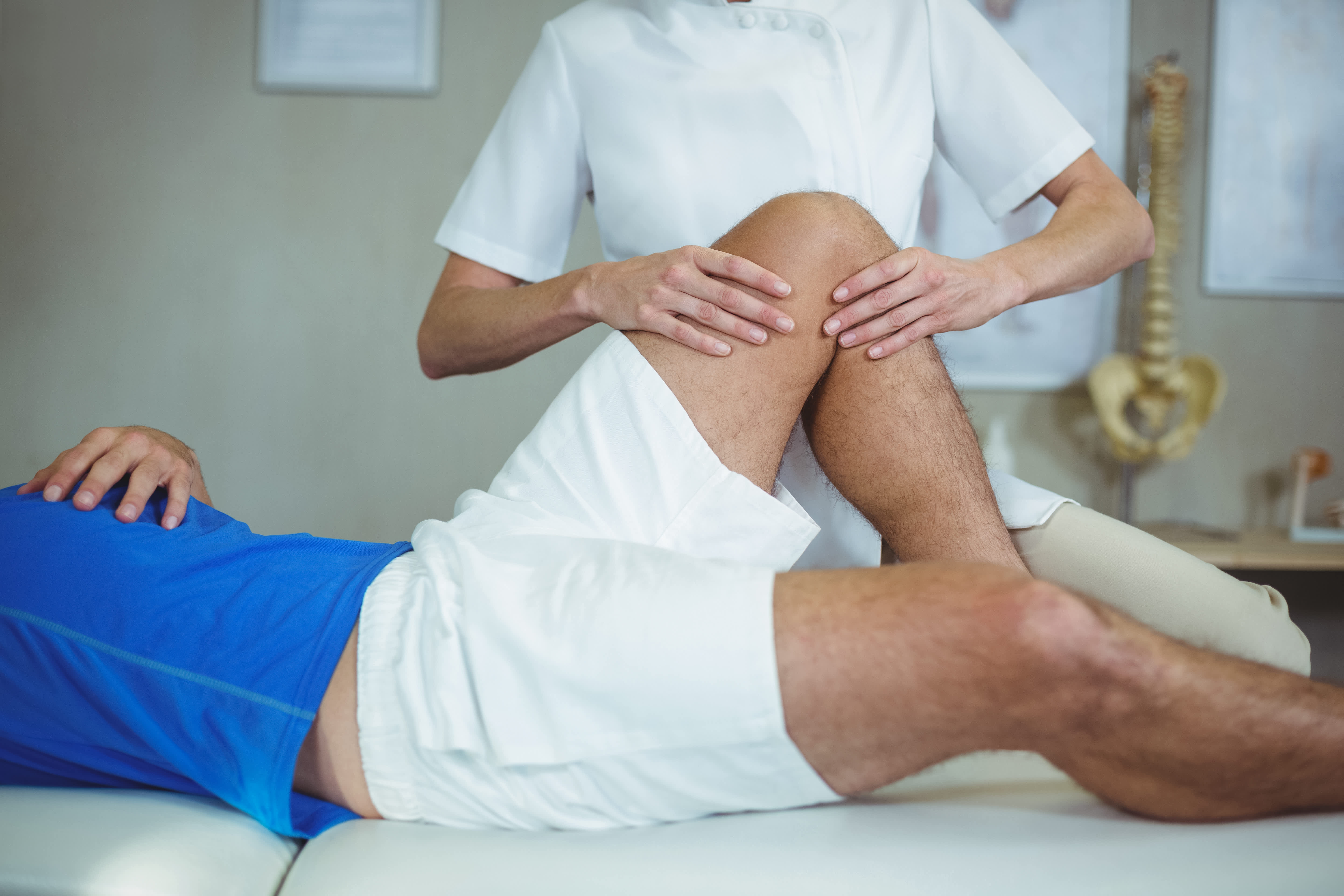 Doctor examining patient's knee in clinic.