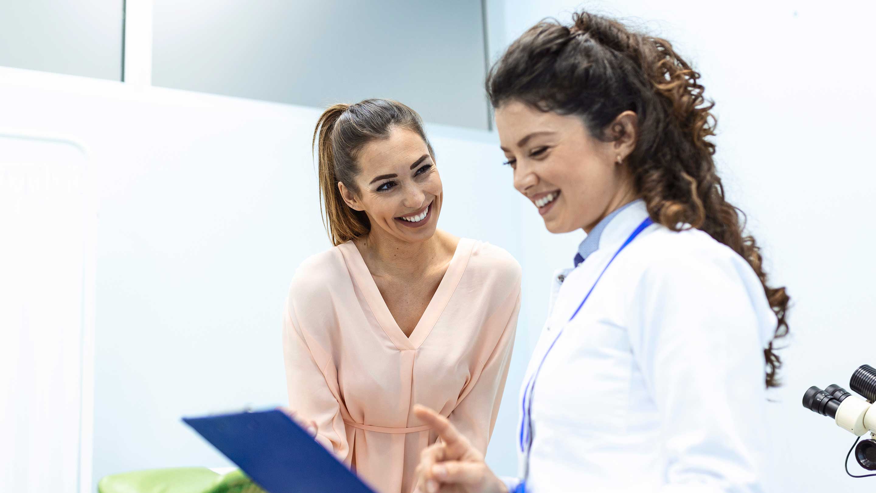 Family physician talking and smiling with woman during exam.