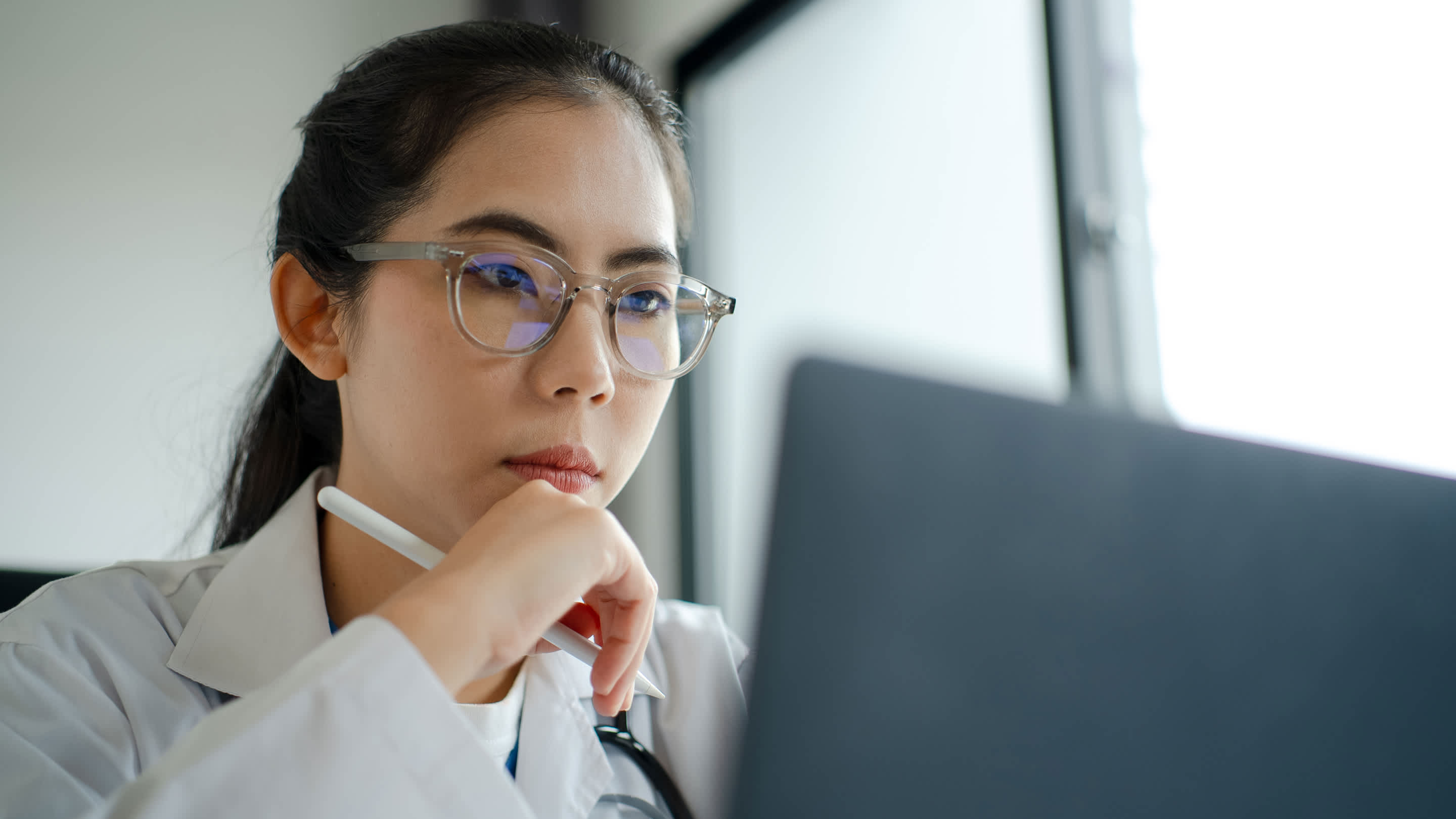 Physician reviewing job opportunities on a laptop