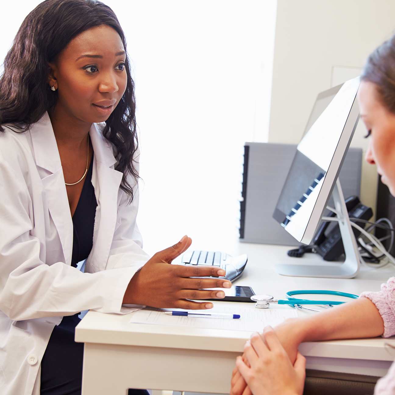 A concerned doctor consults a downcast patient in an office setting.