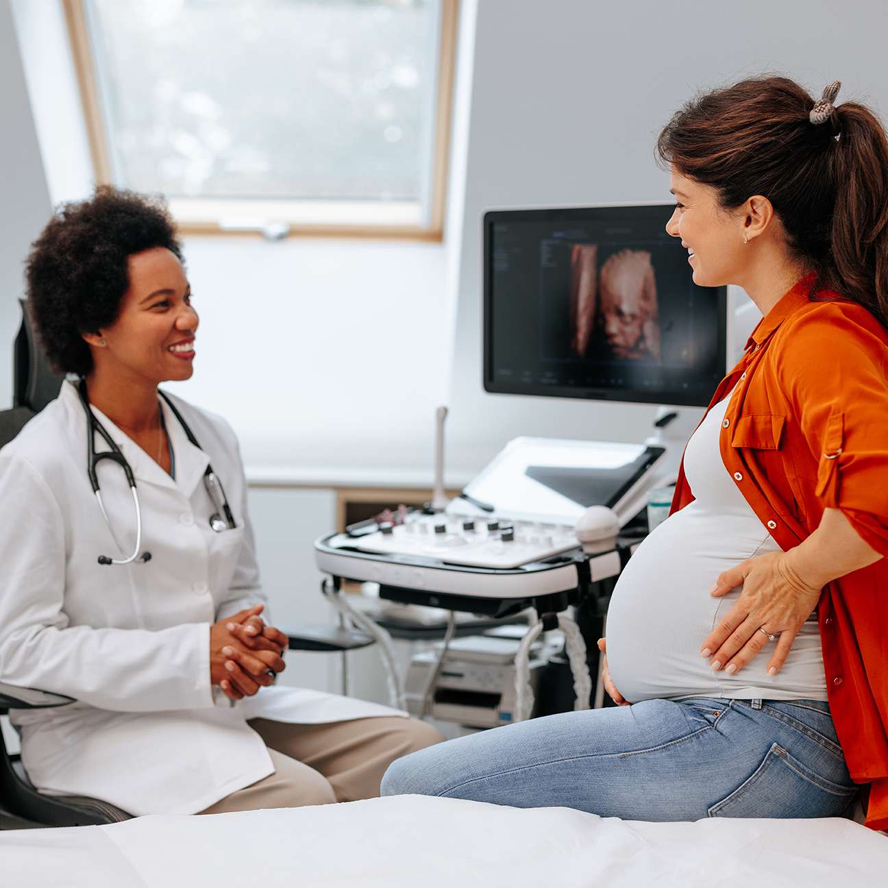 Cheerful physician talking to pregnant patient.