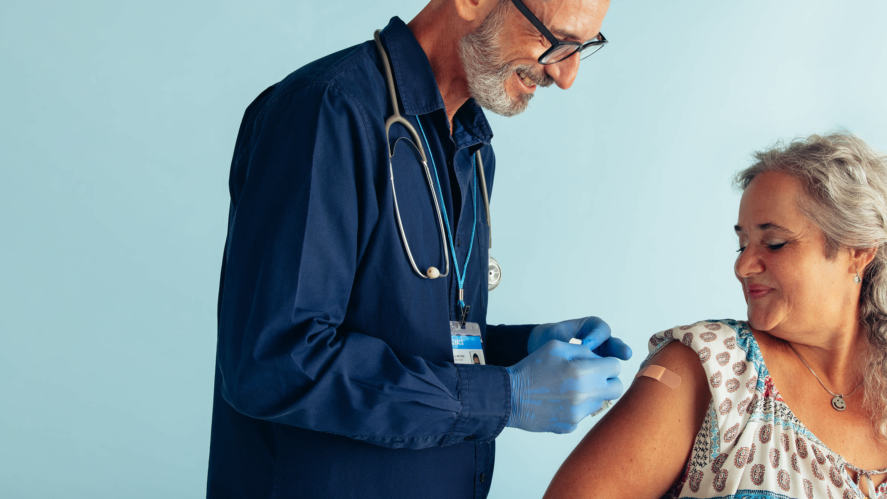 Doctor puts a bandaid on a female patient's arm after a shot or vaccination.