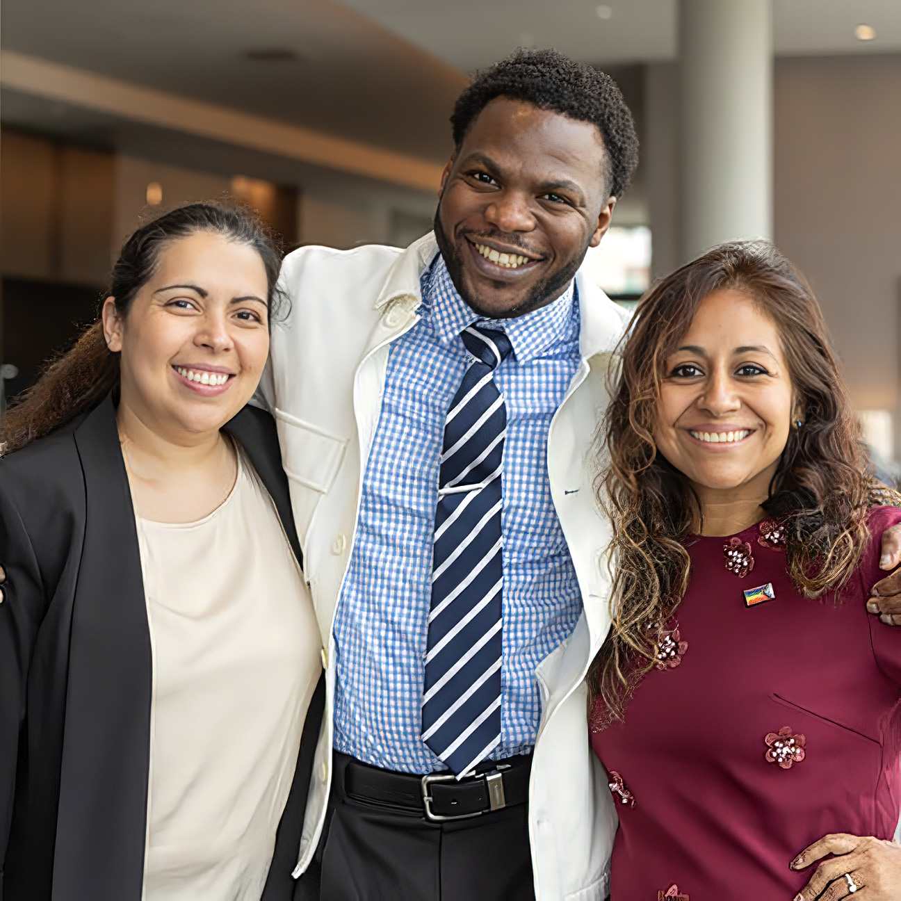 A diverse group of three stand in the lobby of the Loews Hotel in Kansas City for a Leadership event.