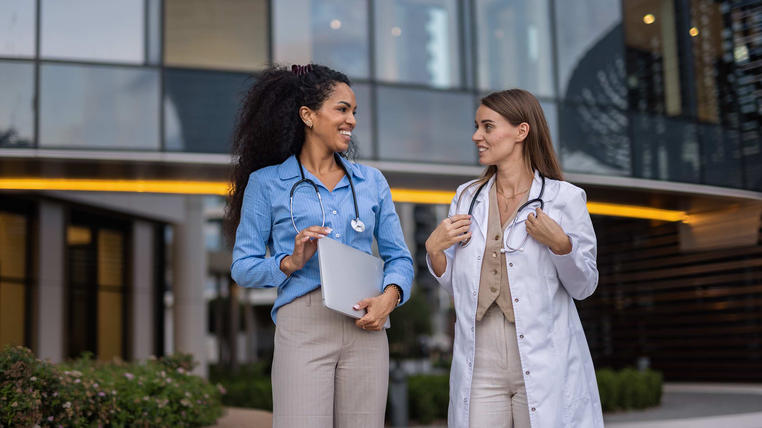 women physicians discuss their careers outside of a hospital building