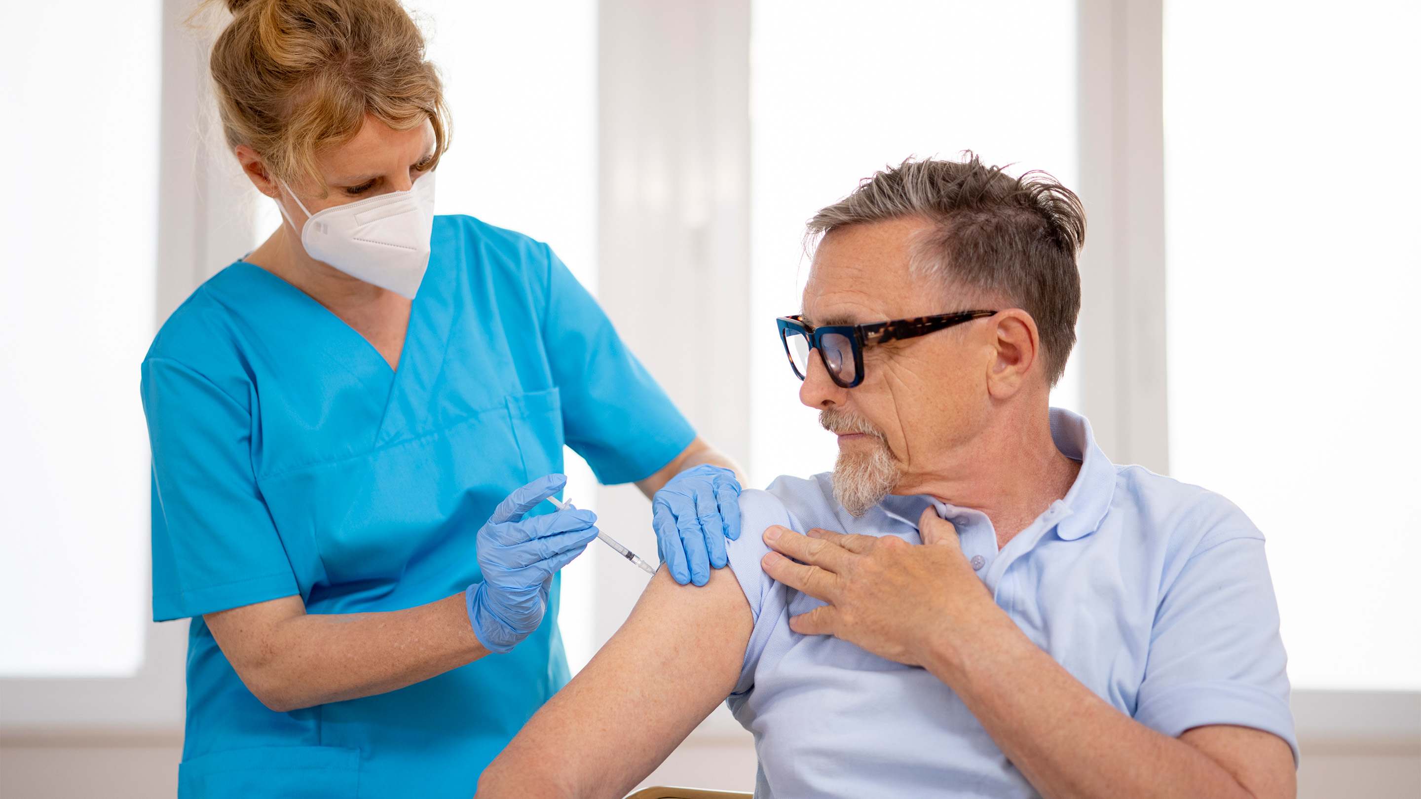 An active male, middle-aged patient receives a vaccination from a female healthcare worker